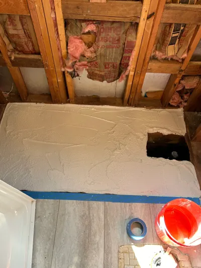 Bathroom wall under renovation with exposed studs, insulation, and a freshly applied mortar patch.