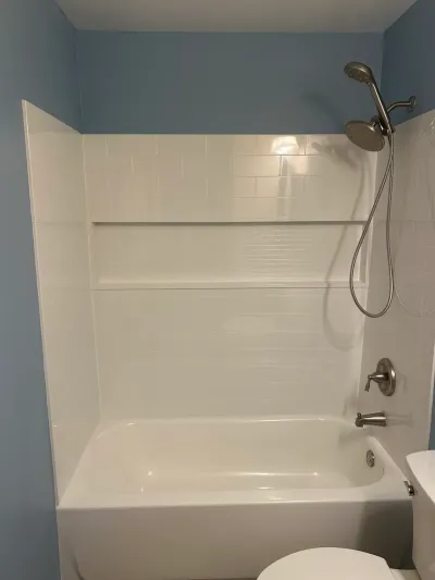 Finished bathtub and shower area with white subway tile, a tile niche, and brushed nickel fixtures.