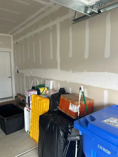 Garage interior with unfinished drywall seams and stacked storage boxes and bins.