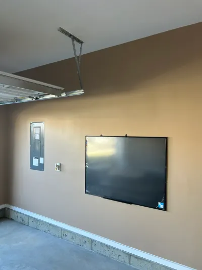 Finished garage wall with an electrical panel, light switch, and a large black wall-mounted board.