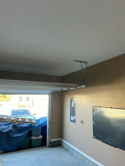Garage under renovation with open door, tan walls, and covered storage items.