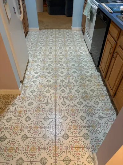 Kitchen with worn floral vinyl flooring, wood cabinets, and a white range before renovation.