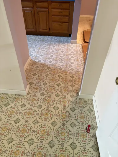 Hallway with floral vinyl flooring leading into a kitchen with oak cabinets before renovation.