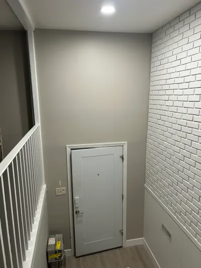 Finished basement stairwell with a white brick accent wall and a paneled door at the base of the stairs.