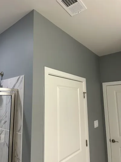A finished bathroom corner with slate blue walls, marble tile accents, and a white paneled door.