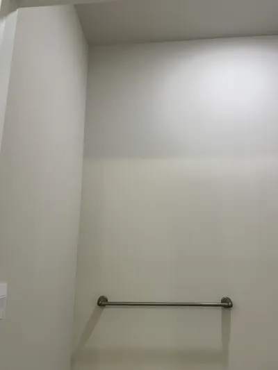 A bathroom wall with a brushed nickel towel bar and a recessed ceiling light overhead.