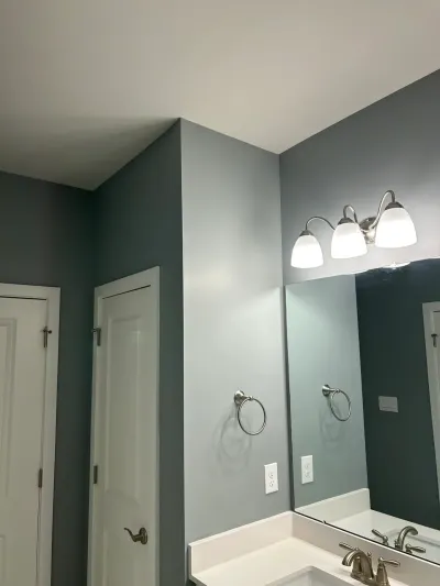 Bathroom vanity with slate-gray walls, a three-light fixture, and a large mirror above the sink.