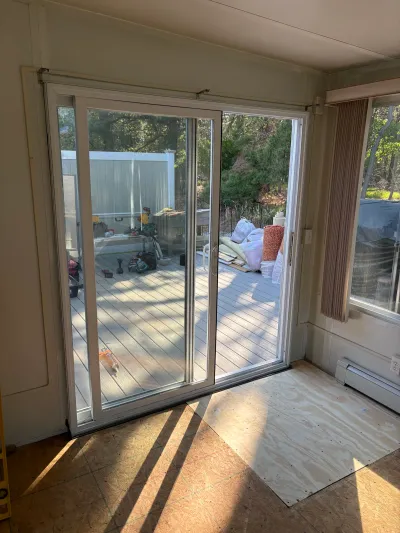 Sliding glass door opens to a deck under renovation, with a plywood subfloor patch inside.