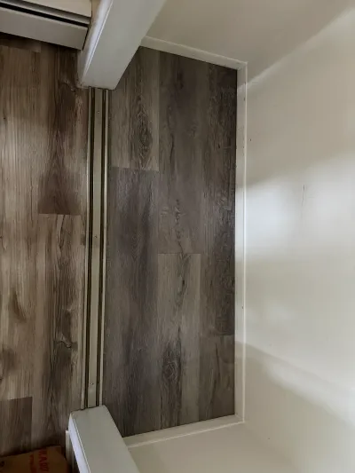 New wood-look vinyl plank flooring installed in a hallway alcove with a metal transition strip.