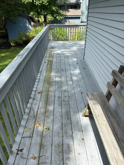 A weathered wood deck with algae staining, a built-in bench, and a white picket railing.