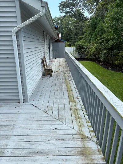 Weathered wooden deck with algae staining running along the side of a house.
