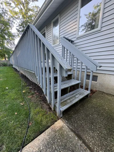 Weathered wood ramp and stairway with peeling paint running along the side of a house.