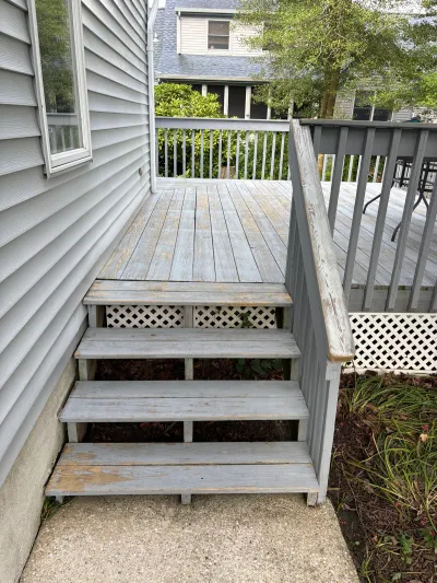 Weathered gray wood deck and stairway with lattice skirting before renovation.