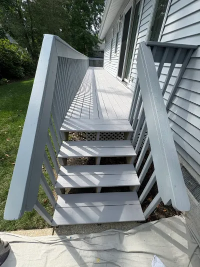 Freshly painted gray wood deck and staircase along the side of a house.