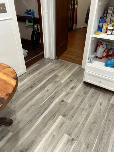 Kitchen with new grey vinyl plank flooring opening into a mudroom and hardwood hallway.