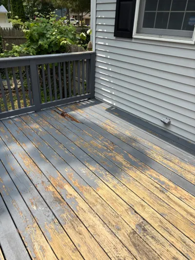 Weathered deck with peeling grey paint and exposed bare wood, next to the house siding.