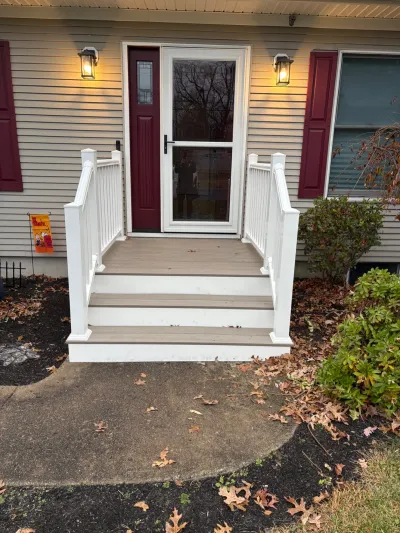 Front porch with composite steps, white railings, and a burgundy entry door flanked by lantern sconces.