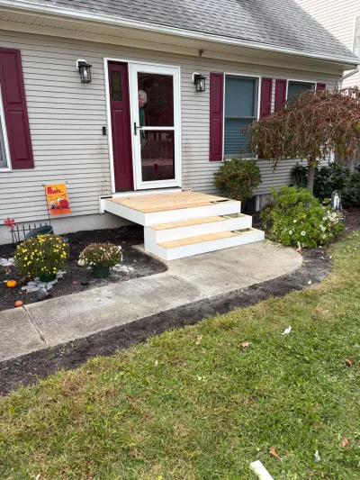 New wood front steps and landing under construction leading to a home's front door.