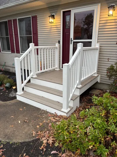 A small composite deck with white railings leads up three steps to a burgundy front door.
