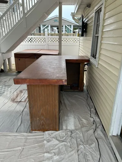 Outdoor deck bar counter and hot tub with protective drop cloths during exterior renovation work.