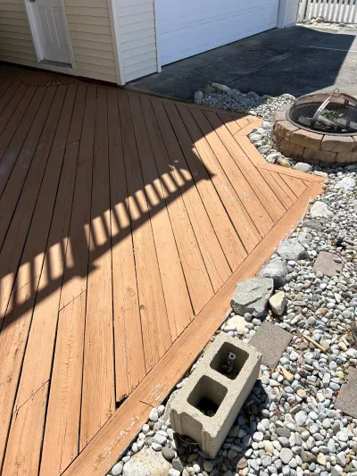 Stained wood deck with diagonal plank pattern bordering a gravel bed and stone fire pit.