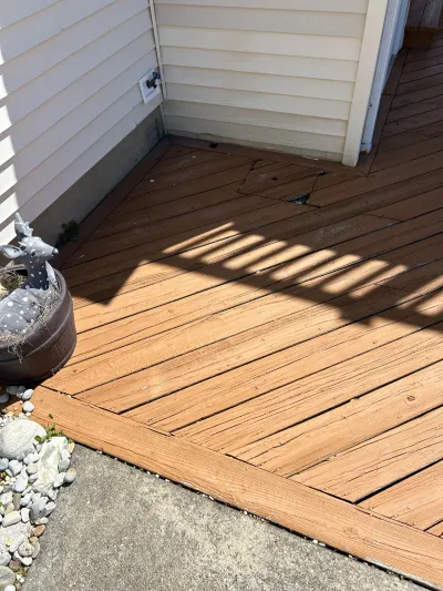 Weathered wood deck with a cracked board near the house entrance, next to a decorative deer planter.